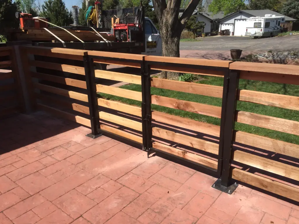iron-wooden-fence-on-the-brick-ground-featuring-standard-fence-company-vehicle-branding-on-the-background-in-denver-co